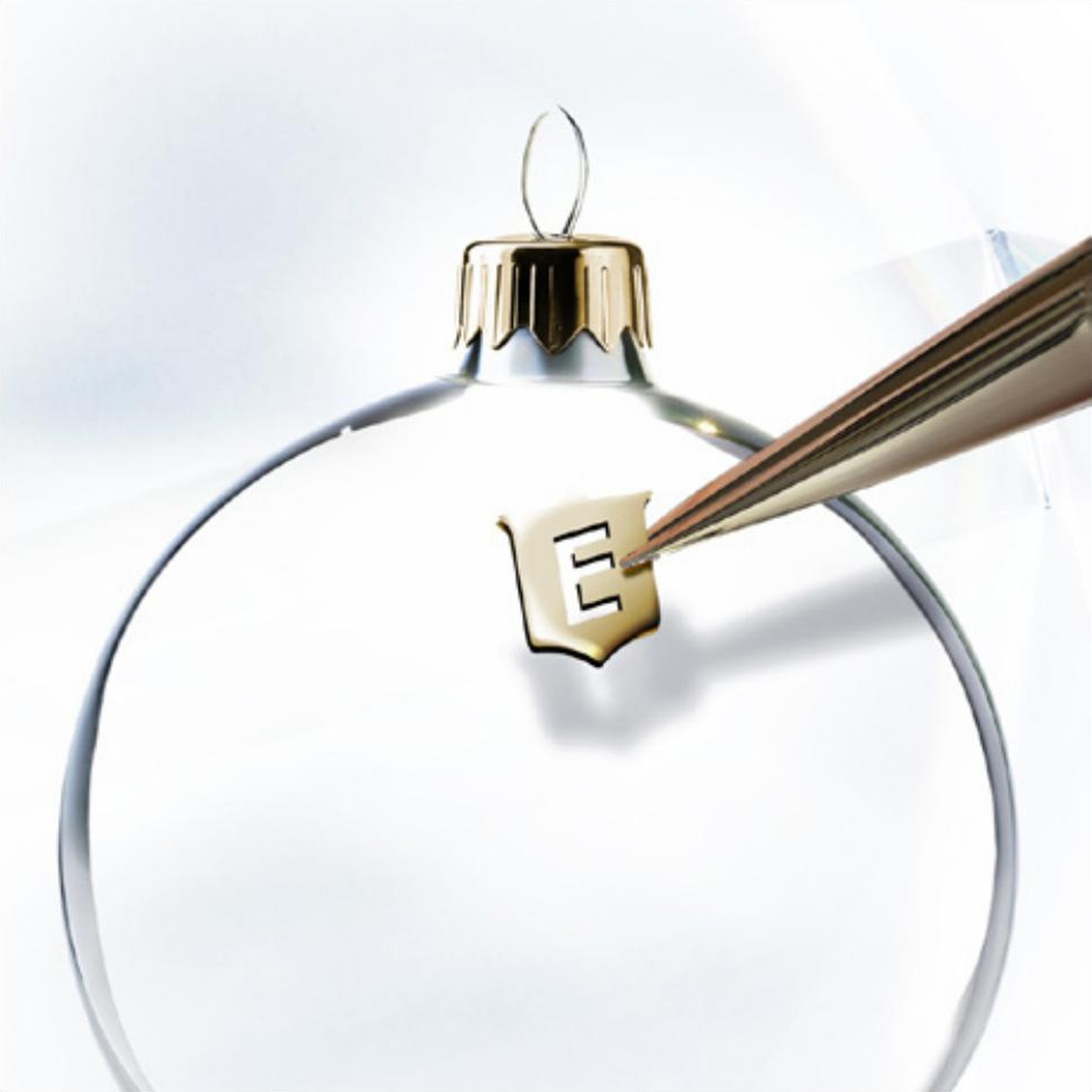 Concept Season's Greetings Eberhard & Co., dettaglio del logo E applicato sulla sommità di una pallina di Natale trasparente